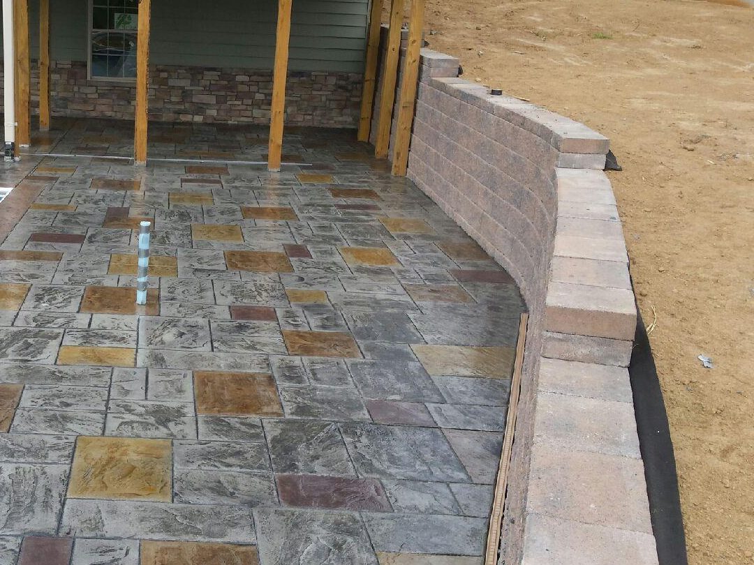 Newly poured stamped concrete pool deck around a rectangular pool behind a Winchester home