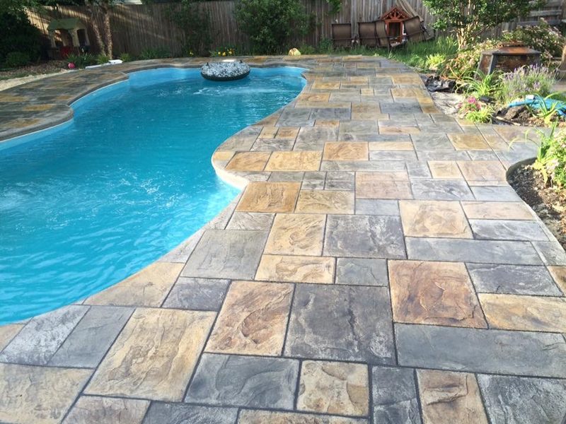 Tan and gray flagstone stamped concrete pool deck around a freeform pool