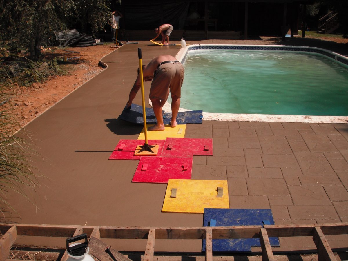 Blackwater crew stamping a colored concrete pool deck around a pool