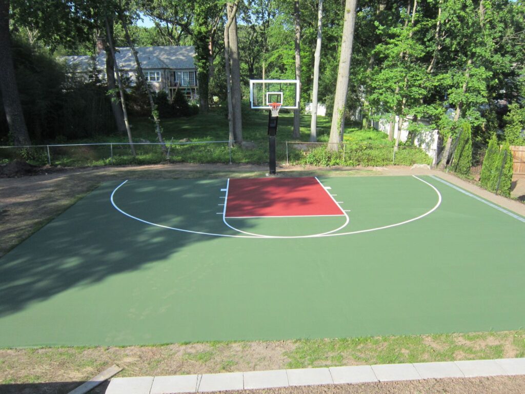 Green and red painted concrete backyard basketball court in Winchester VA