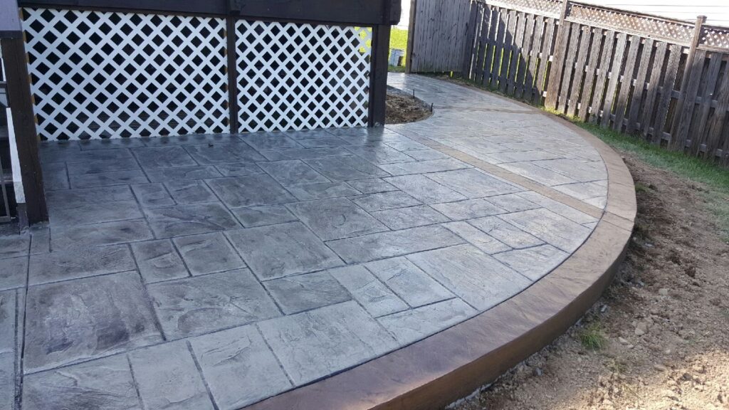 Curved concrete patio beside white lattice deck skirting in Winchester VA